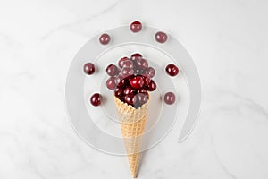 Fresh summer cherry berries in waffle ice cream cone on white background. Food composition. flat lay