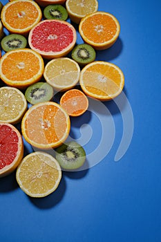 Fresh summer fruits on blue background. Flat lay. Tropical summer mix grapefruit, orange, mandarin, kiwi, lemon.