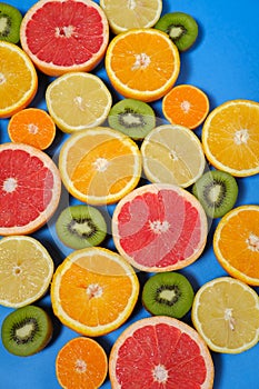 Fresh summer fruits on blue background. Flat lay. Tropical summer mix grapefruit, orange, mandarin, kiwi, lemon