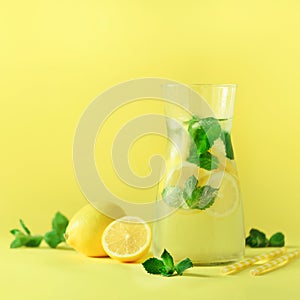 Fresh summer fruits water or lemonade with mint, ice, lemon on yellow background. Square crop. Copy space. Summer