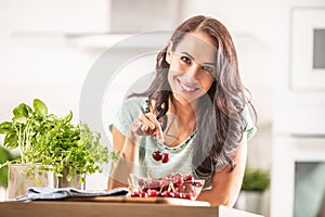 Fresh summer harvest of cherries brought indoors by a good-looking woman in a seethrough bowl photo