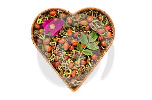 Fresh summer rose hips in heart form wicker basket isolated