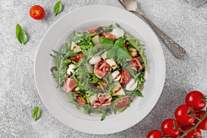 Fresh summer salad with arugula, melon, prosciutto and mozzarella cheese on concrete background, Healthy food. Top view