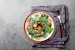 Fresh summer salad with baby spinach and tomatoes cherry. Top view, copy space. Slate gray background