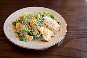 Fresh summer salad Ceasar with eggs, lettuce, chicken and parmesan cheese on white plate on wooden background; healthy concept; si