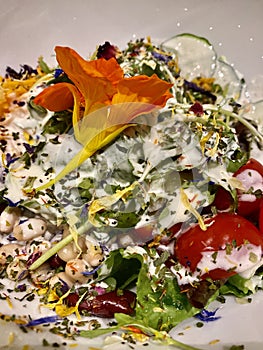 Fresh summer salad with edible flowers nasturtium, borage flowers in a bowl. Top view