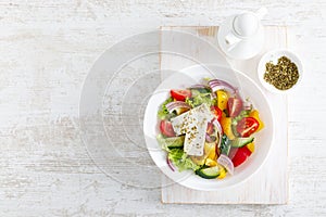 Fresh summer vegetable salad with lettuce, tomato, cucumber, bell pepper, onion and feta cheese