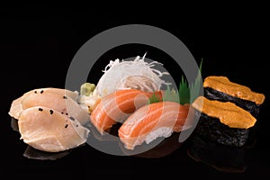 Fresh Sushi set. Sushi and sashimi served on a black reflective surface. Isolated on a black.