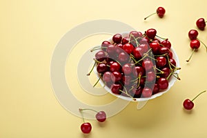 Fresh sweet cherries bowl on beige background, top view