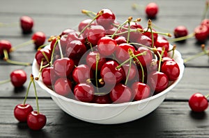 Fresh sweet cherries bowl on black background, top view