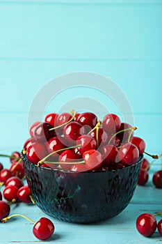 Fresh sweet cherries bowl on blue background, top view