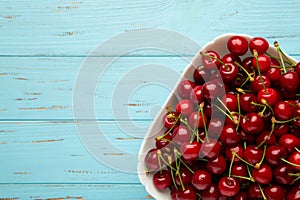 Fresh sweet cherries bowl on blue background, top view