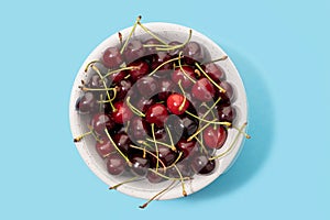 Fresh sweet cherries bowl isolated on blue background