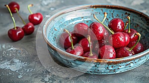 Fresh sweet cherries bowl with leaves in water drops on blue stone background, top view