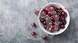 Fresh sweet cherries bowl with leaves in water drops on blue stone background, top view