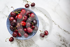 Fresh sweet cherries bowl on marble background. Top view with copy space