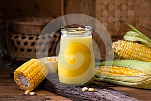 Fresh sweet corn juice (corn milk) and corn on wood background