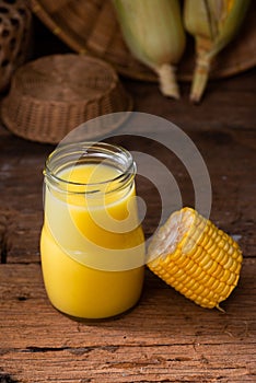 Fresh sweet corn juice corn milk and corn on wood background