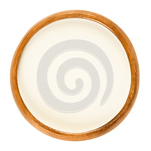 Fresh sweet cream in wooden bowl over white