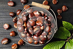 Fresh sweet edible chestnuts on black wooden  table, flat lay