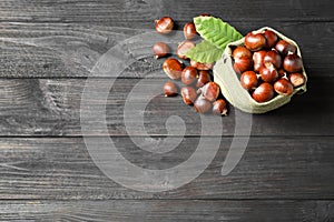 Fresh sweet edible chestnuts on black wooden table, flat lay. Space for text