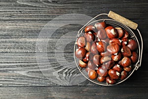 Fresh sweet edible chestnuts on black wooden  table, top view. Space for text