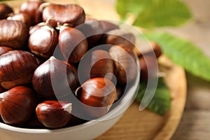 Fresh sweet edible chestnuts in bowl on table, closeup