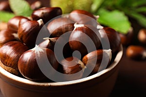 Fresh sweet edible chestnuts in bowl on table, closeup