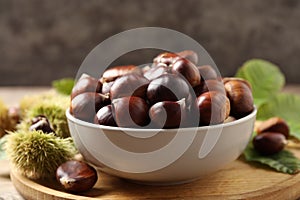 Fresh sweet edible chestnuts in bowl on wooden board