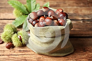 Fresh sweet edible chestnuts in sack on wooden table