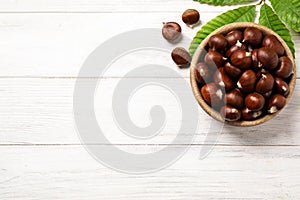 Fresh sweet edible chestnuts on white wooden table, flat lay. Space for text