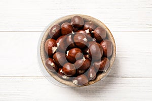 Fresh sweet edible chestnuts on white wooden table, top view