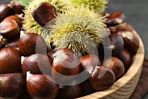 Fresh sweet edible chestnuts in wooden bowl, closeup
