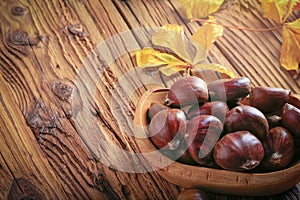 Fresh sweet edible chestnuts in a wooden bowl on a wooden table. Copy space for text