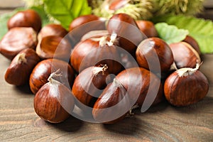 Fresh sweet edible chestnuts on wooden table, closeup