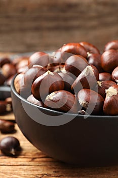 Fresh sweet edible chestnuts on wooden table, closeup