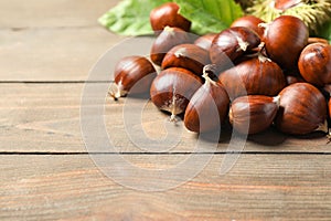 Fresh sweet edible chestnuts on wooden table, closeup. Space for text