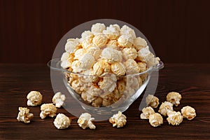 Fresh, sweet popcorn with caramel, golden color on the background of a dark wooden table