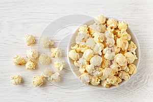 Fresh, sweet popcorn with caramel, golden color on a white wooden table