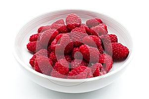 Fresh and sweet raspberries in a white bowl, isolated on white background