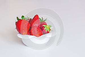 Fresh sweet strawberries in a white bowl on a white background