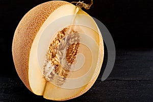 Fresh sweet yellow melon sliced on wooden black background. Raw organic melon on wooden dark surface close up