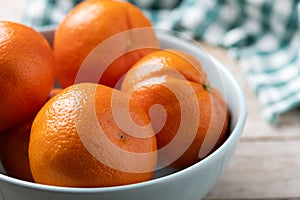 Fresh tangerines in bowl on wooden table