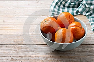 Fresh tangerines in bowl on wooden table