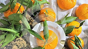 Fresh tangerines clementines with leaves on white fabric, top view