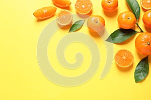 Fresh tangerines and leaves on color background, flat lay with space for text.