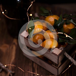 Fresh tangerines with leaves in an old box. On wooden background