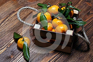 Fresh tangerines with leaves in an old box. On wooden background