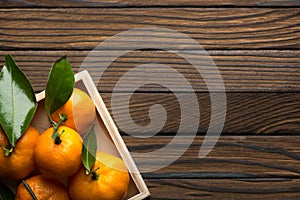 Fresh tangerines with leaves in wooden box on the table