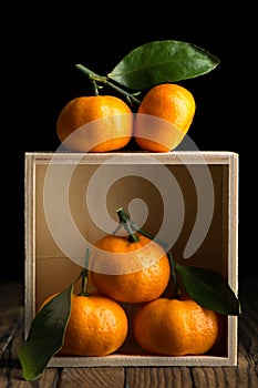 Fresh tangerines with leaves in wooden box on the table